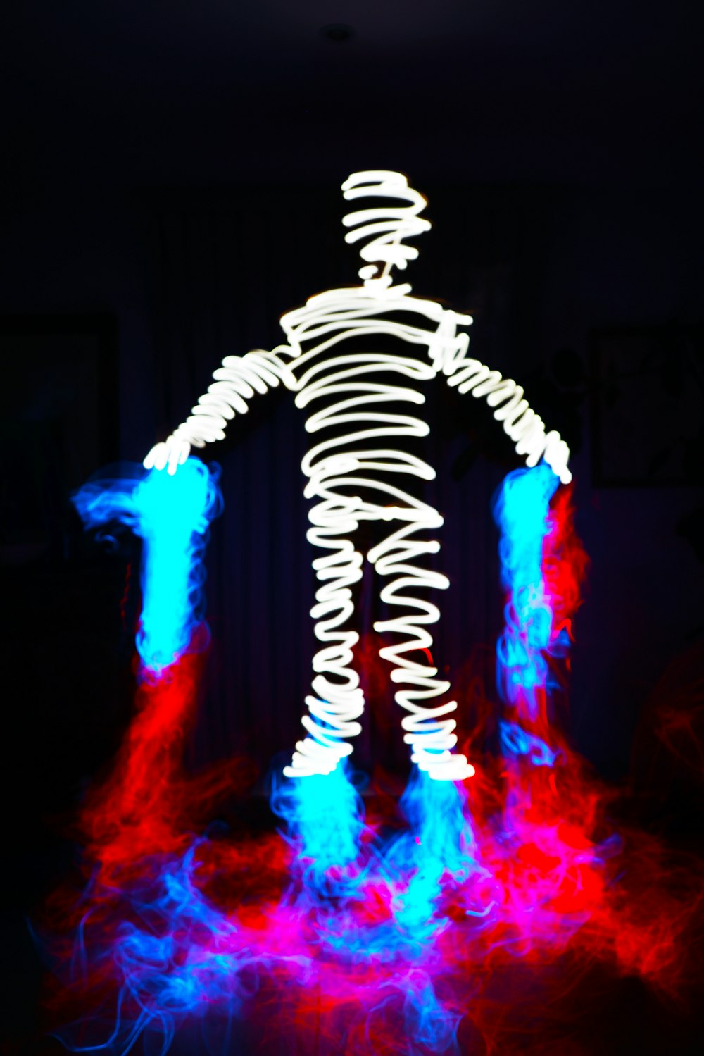 Una persona parada en la oscuridad con una pintura de luz en ella