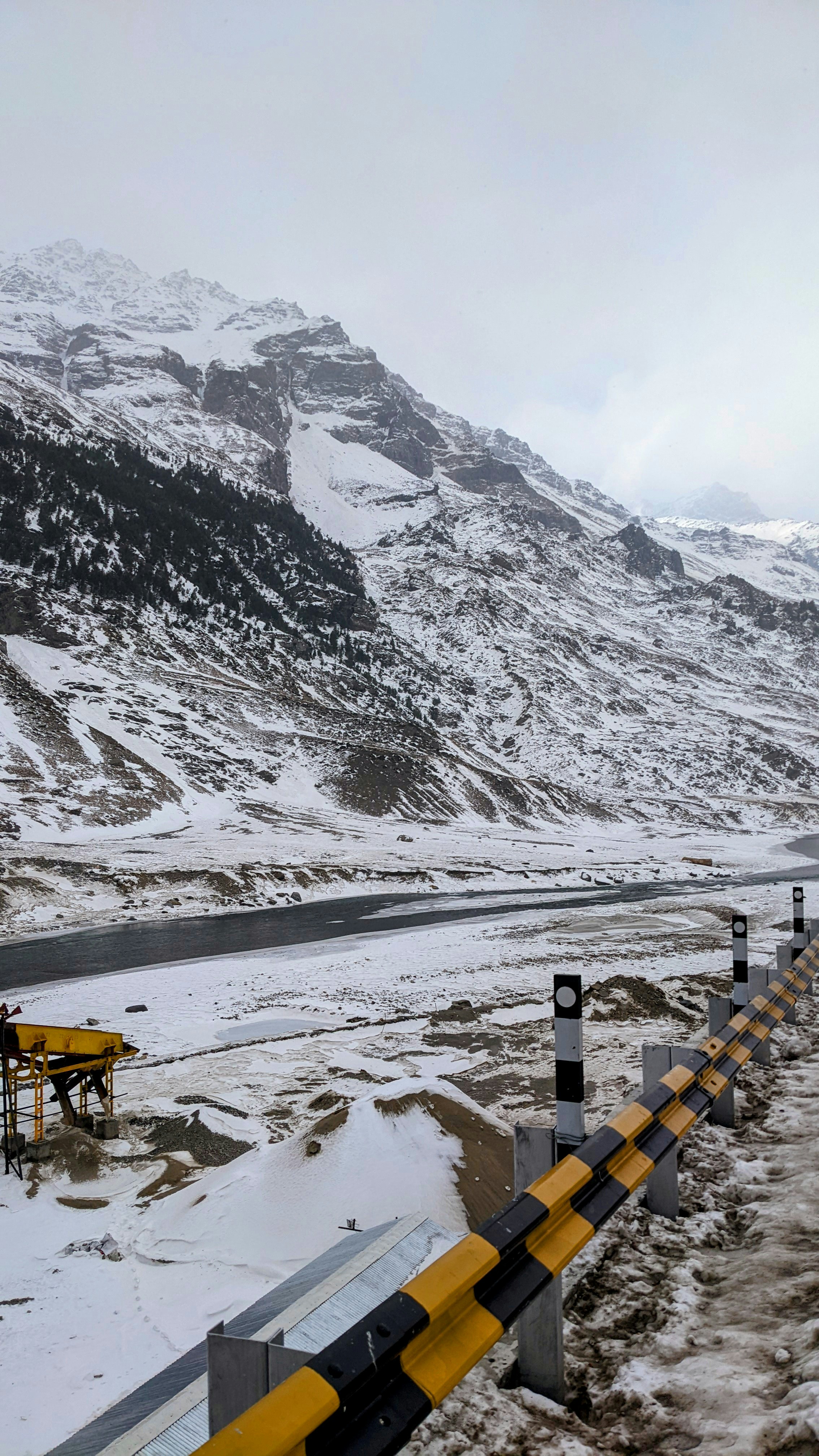 Una montagna innevata con un guard rail giallo e nero