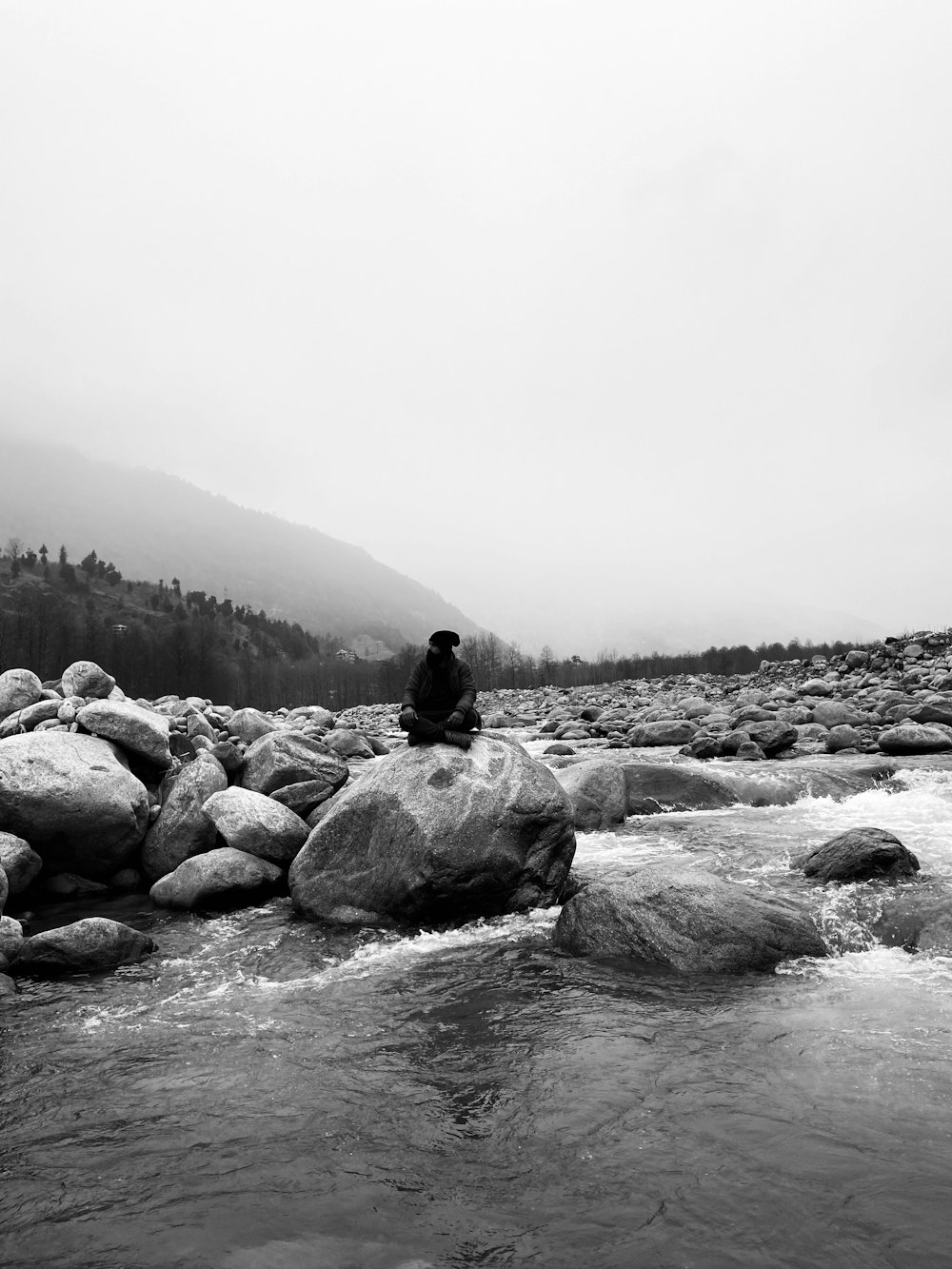 a person sitting on a rock in a river