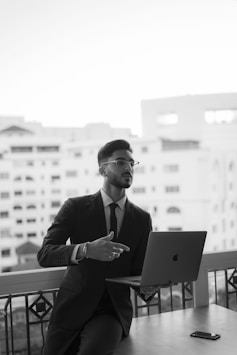 a man in a suit sitting at a table with a laptop