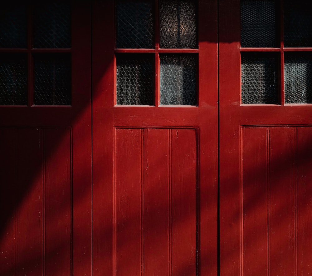 a red door with two windows and a bench in front of it