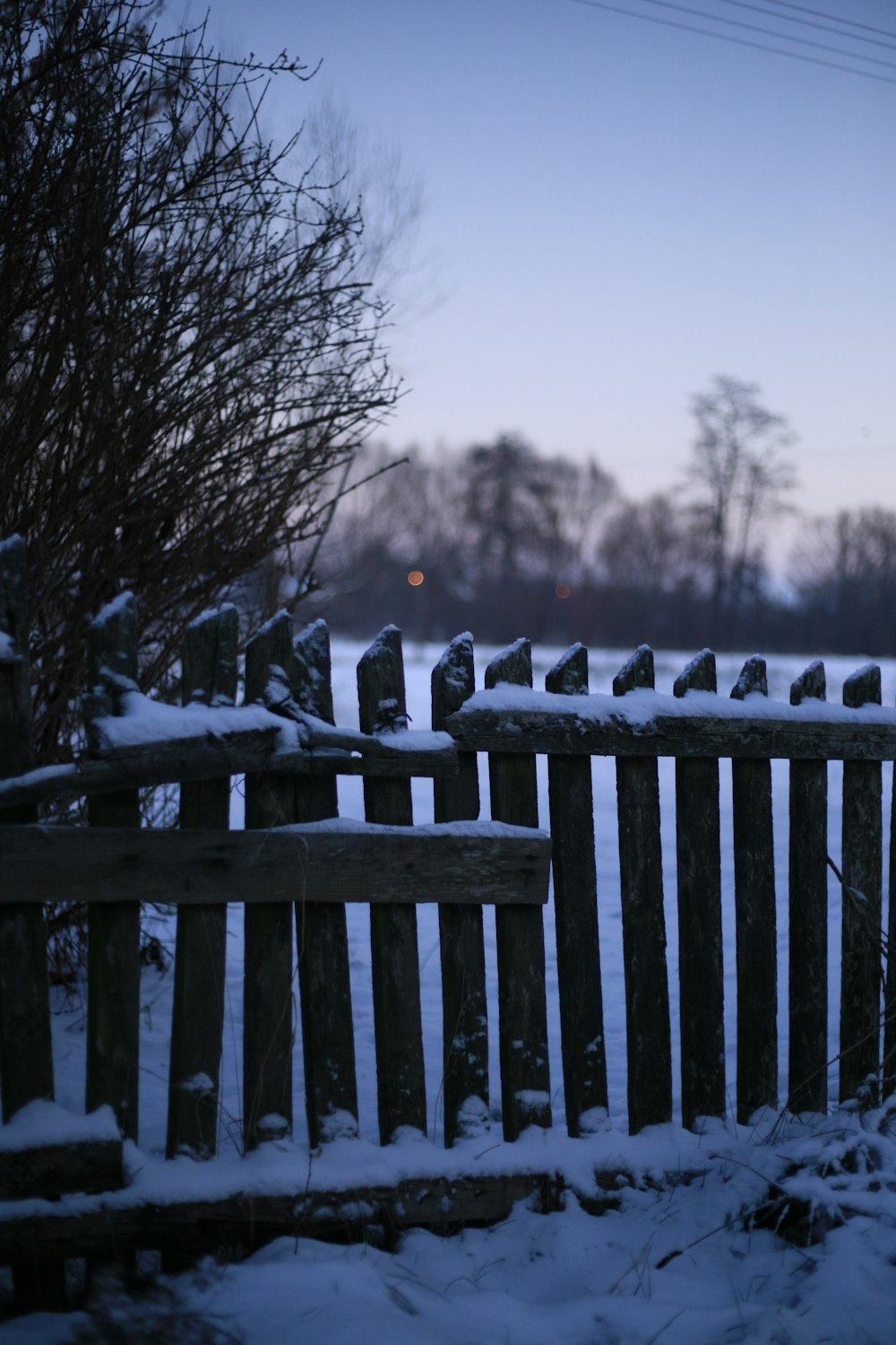 a wooden fence covered in snow next to a field