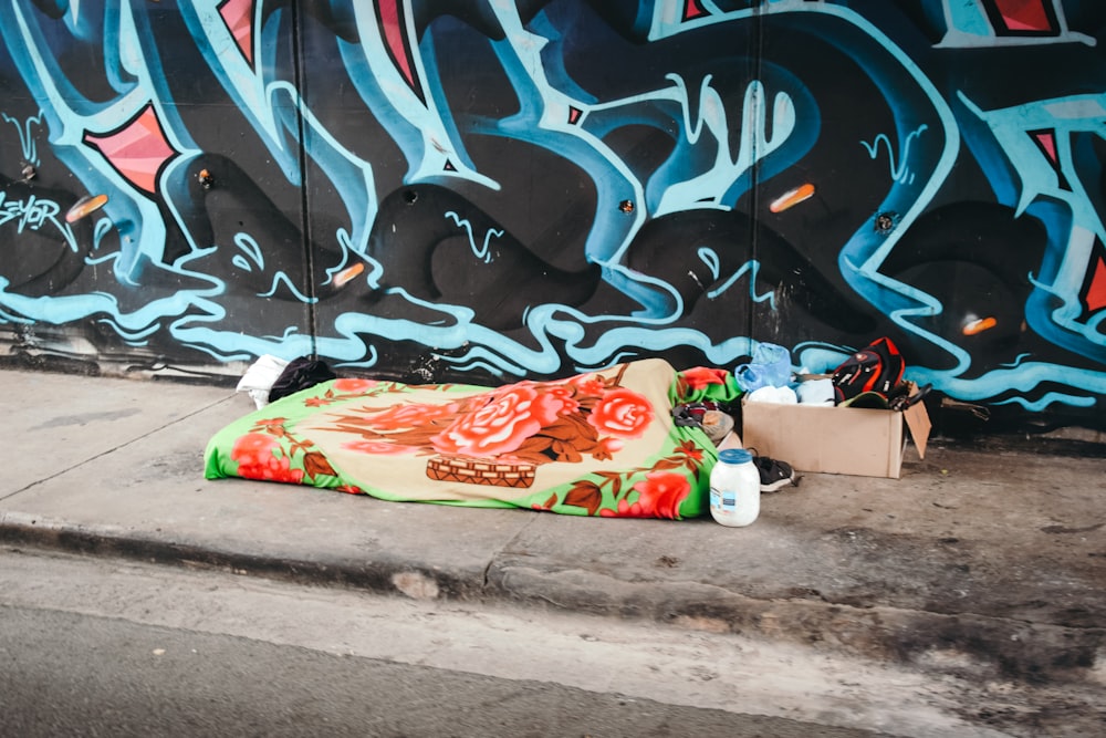 a blanket on the ground next to a wall with graffiti