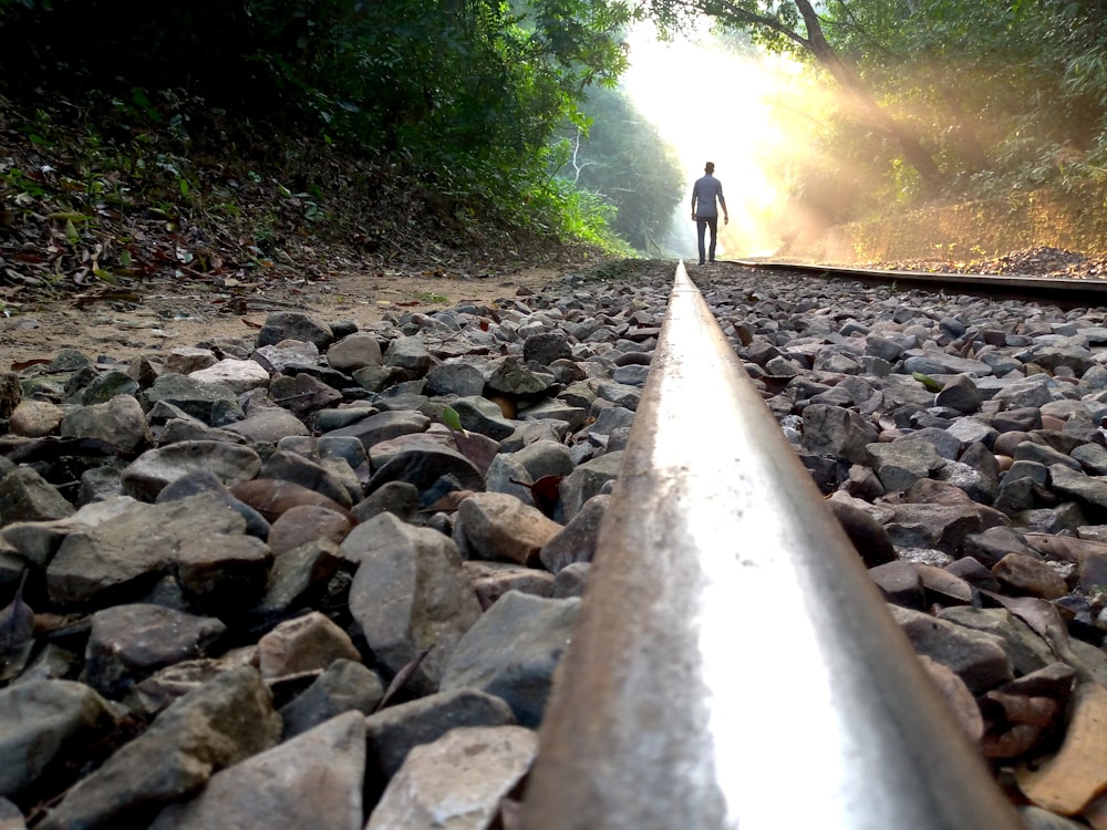 Un hombre parado en una vía de tren rodeado de rocas