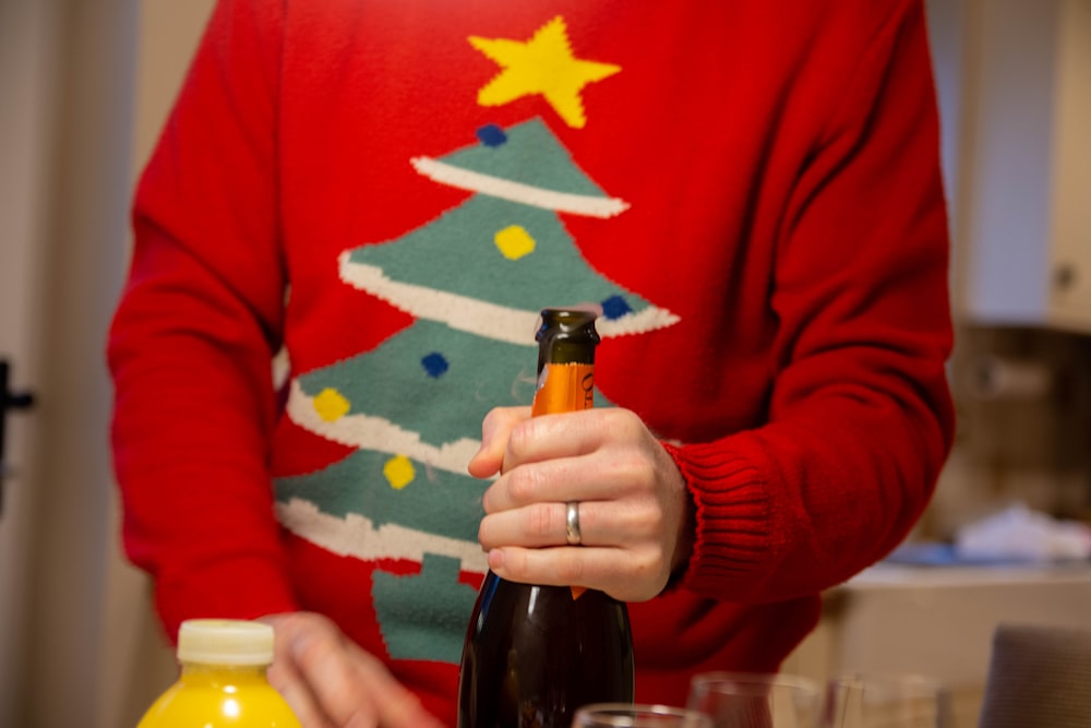 a person holding a bottle of wine in front of a christmas tree