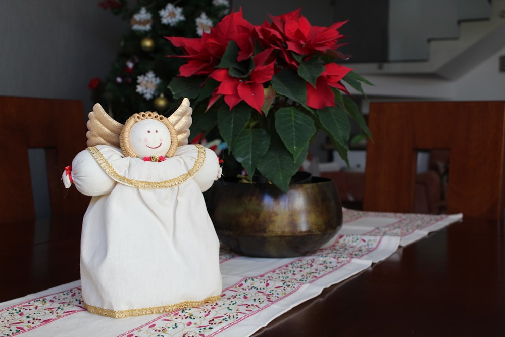 a small angel figurine sitting on a table next to a potted plant