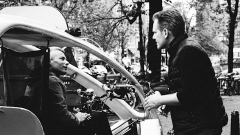 a black and white photo of a man talking to another man