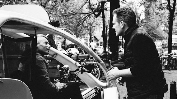 a black and white photo of a man talking to another man