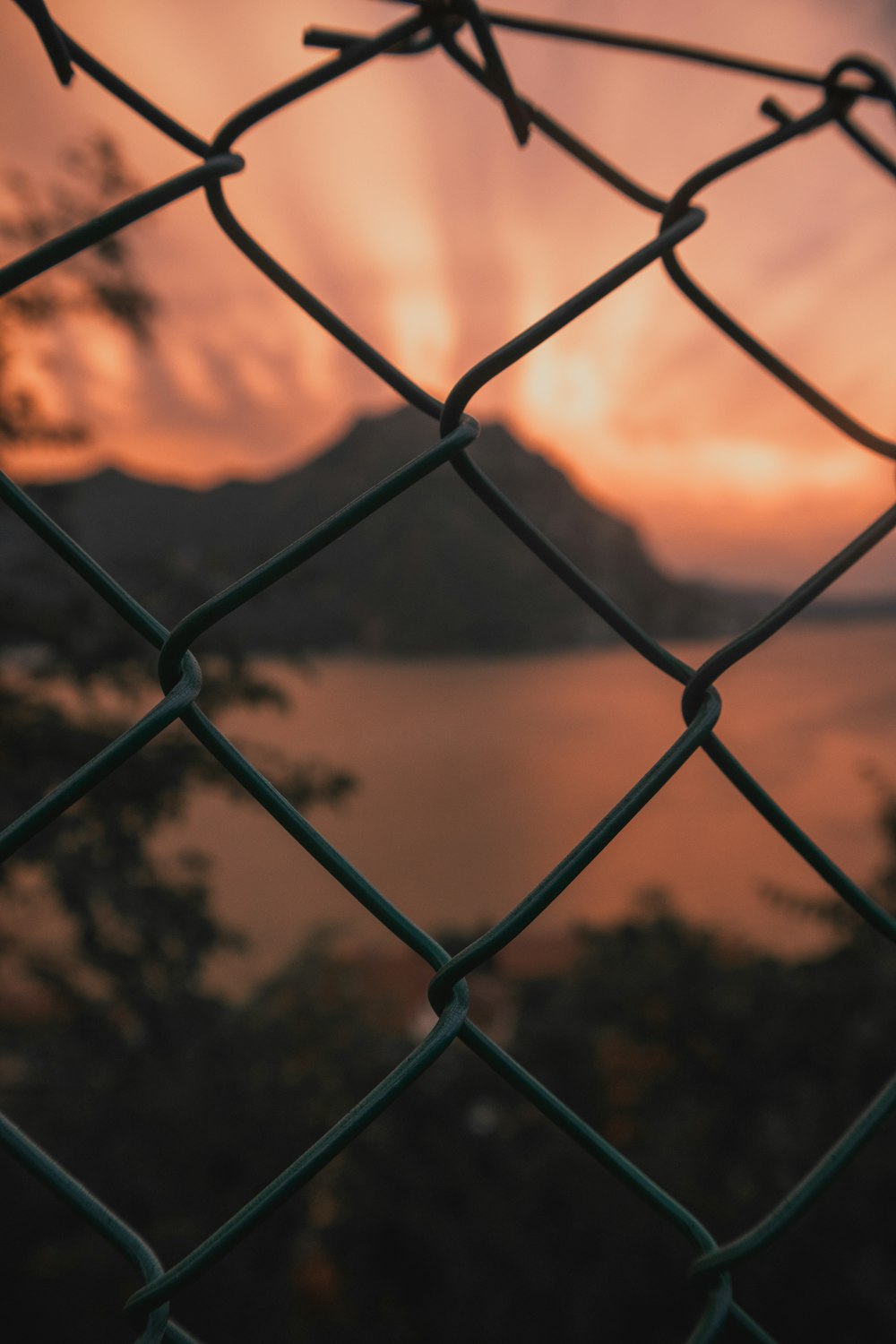 a chain link fence with a sunset in the background