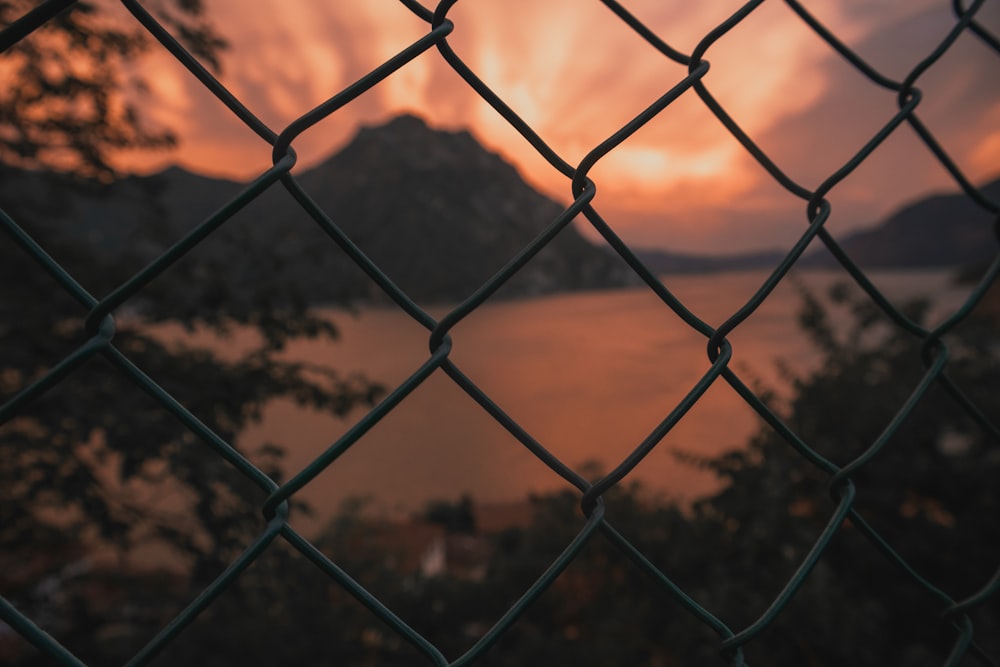 a sunset seen through a chain link fence