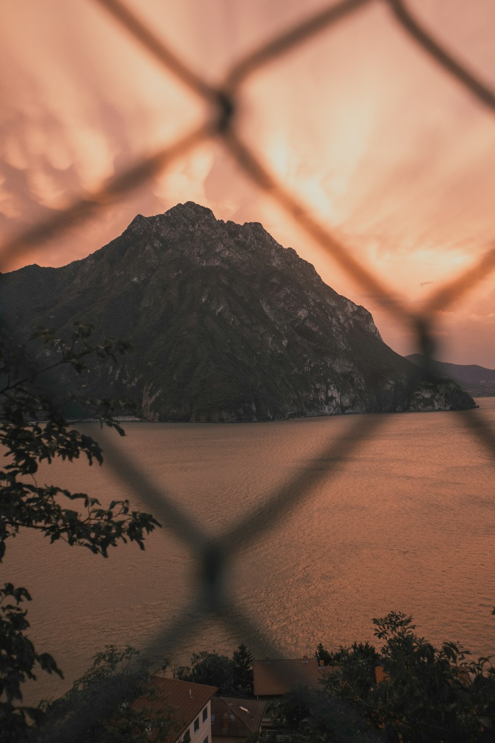 Blick auf einen See durch einen Maschendrahtzaun