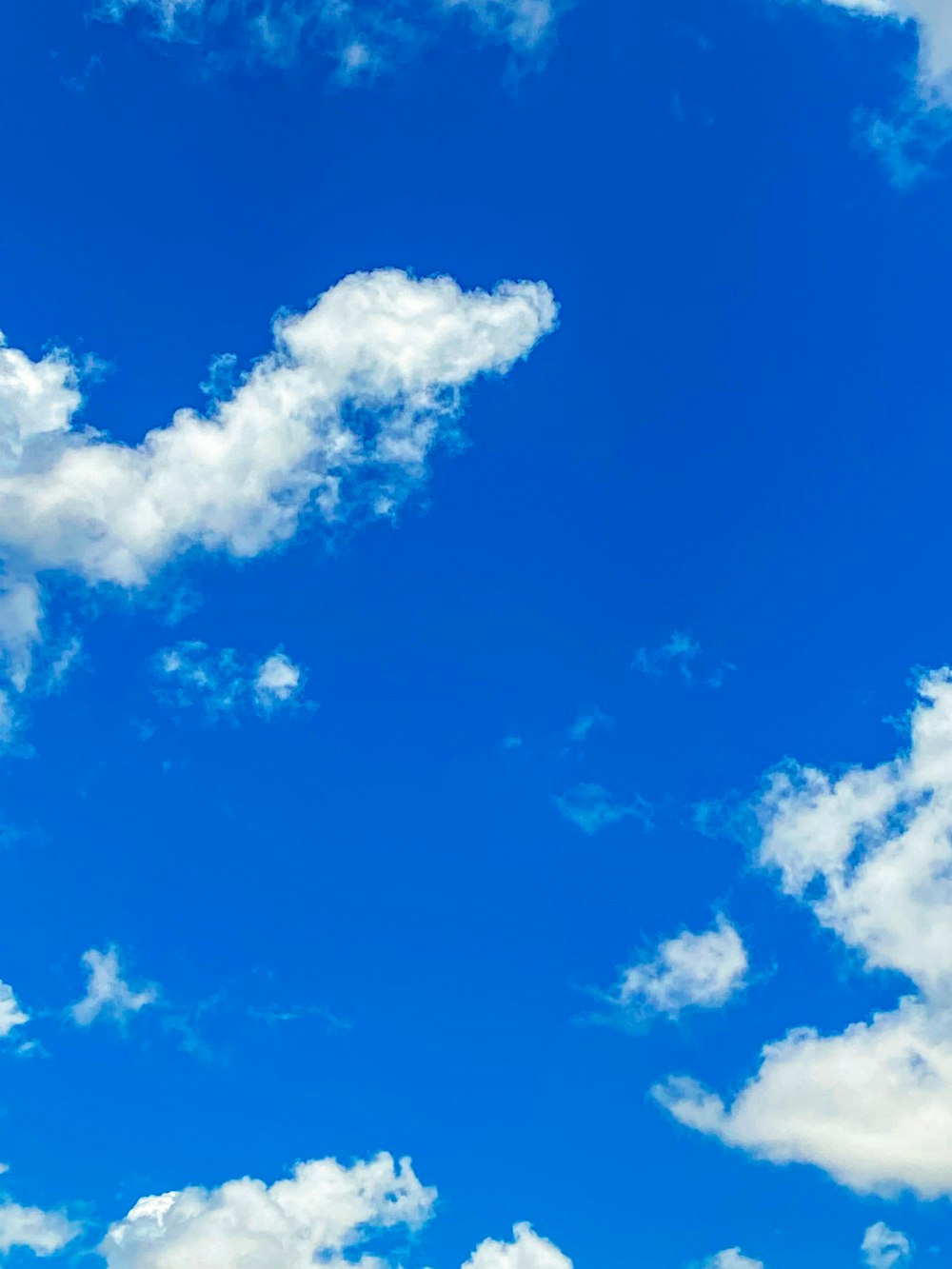 Un avión volando a través de un cielo azul con nubes blancas