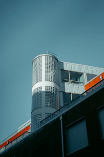 A sleek modern office building designed by turuncuköprü, showcasing sharp lines and black-orange accents.