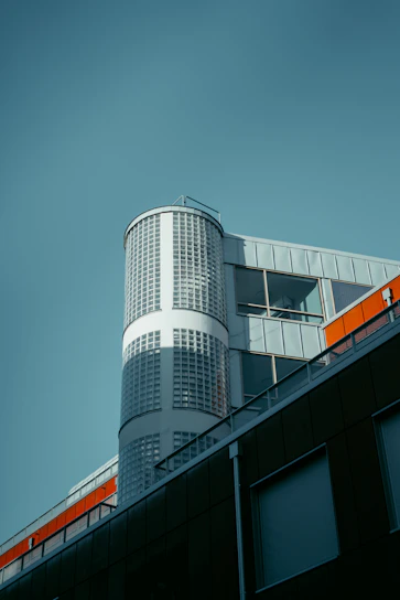 A sleek modern office building designed by turuncuköprü, showcasing sharp lines and black-orange accents.