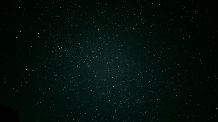 A serene night sky filled with twinkling stars and subtle zodiac symbols glowing softly.