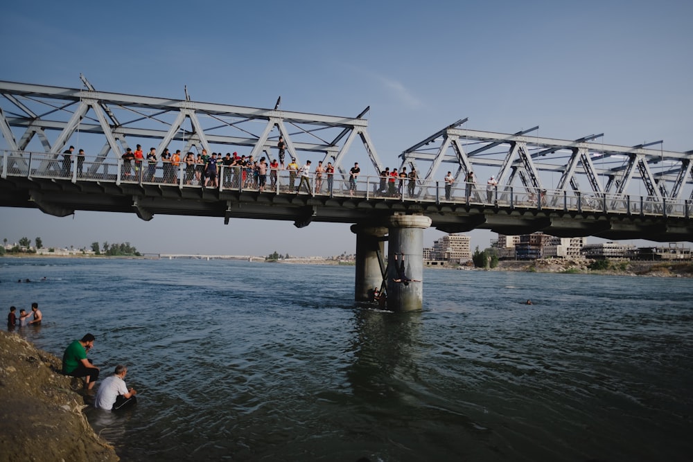 a group of people crossing a bridge over a body of water