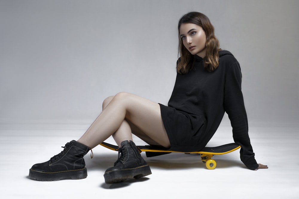 a woman sitting on top of a skateboard