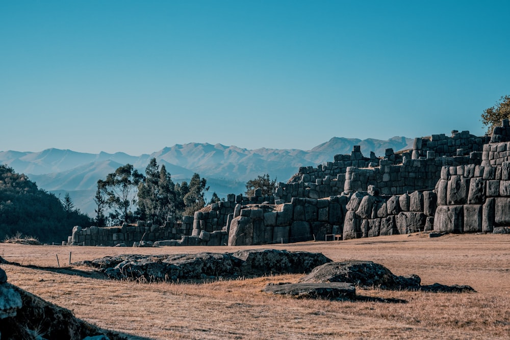 a stone structure in a field with mountains in the background