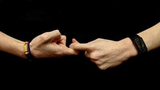 two hands holding each other with bracelets on them