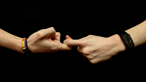 two hands holding each other with bracelets on them