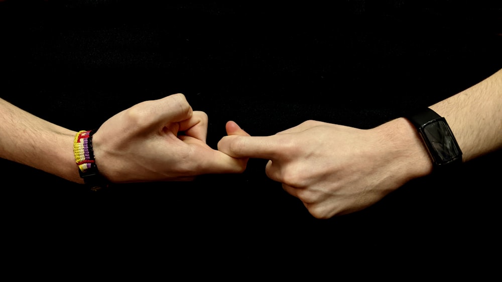 two hands holding each other with bracelets on them