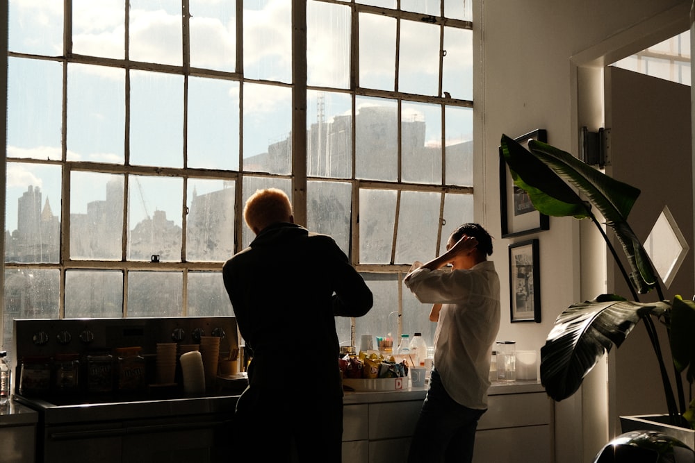 a couple of people standing in front of a window