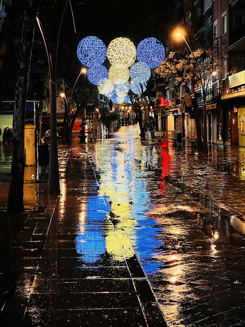 Eine Stadtstraße bei Nacht mit Lichtern und Regenschirmen