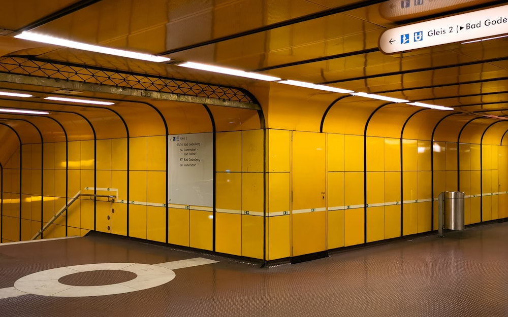 a subway station with yellow walls and metal railings