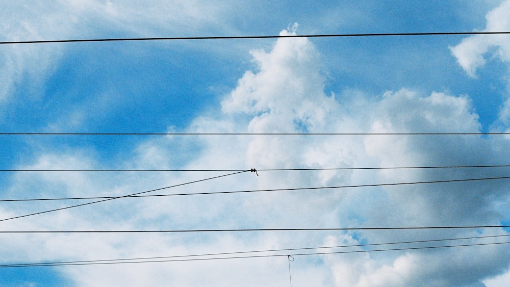 Stromleitungen und Drähte vor blauem Himmel mit Wolken