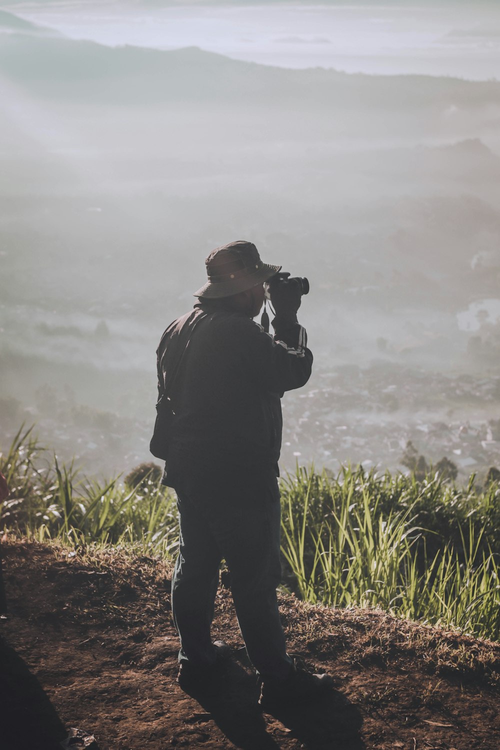 a man standing on top of a hill with a camera
