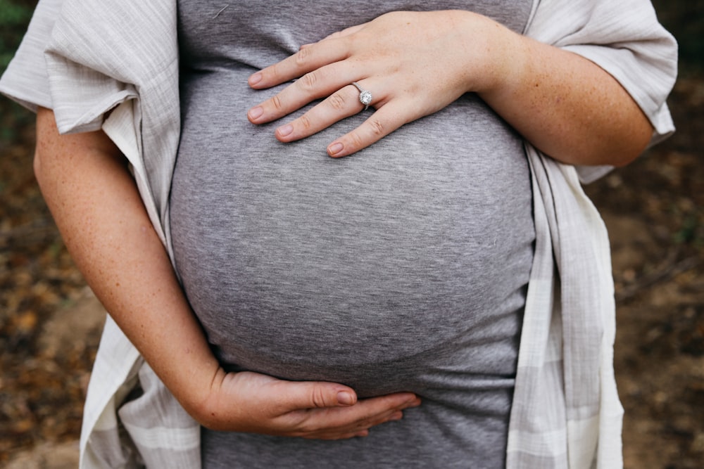 uma mulher grávida segurando sua barriga em suas mãos