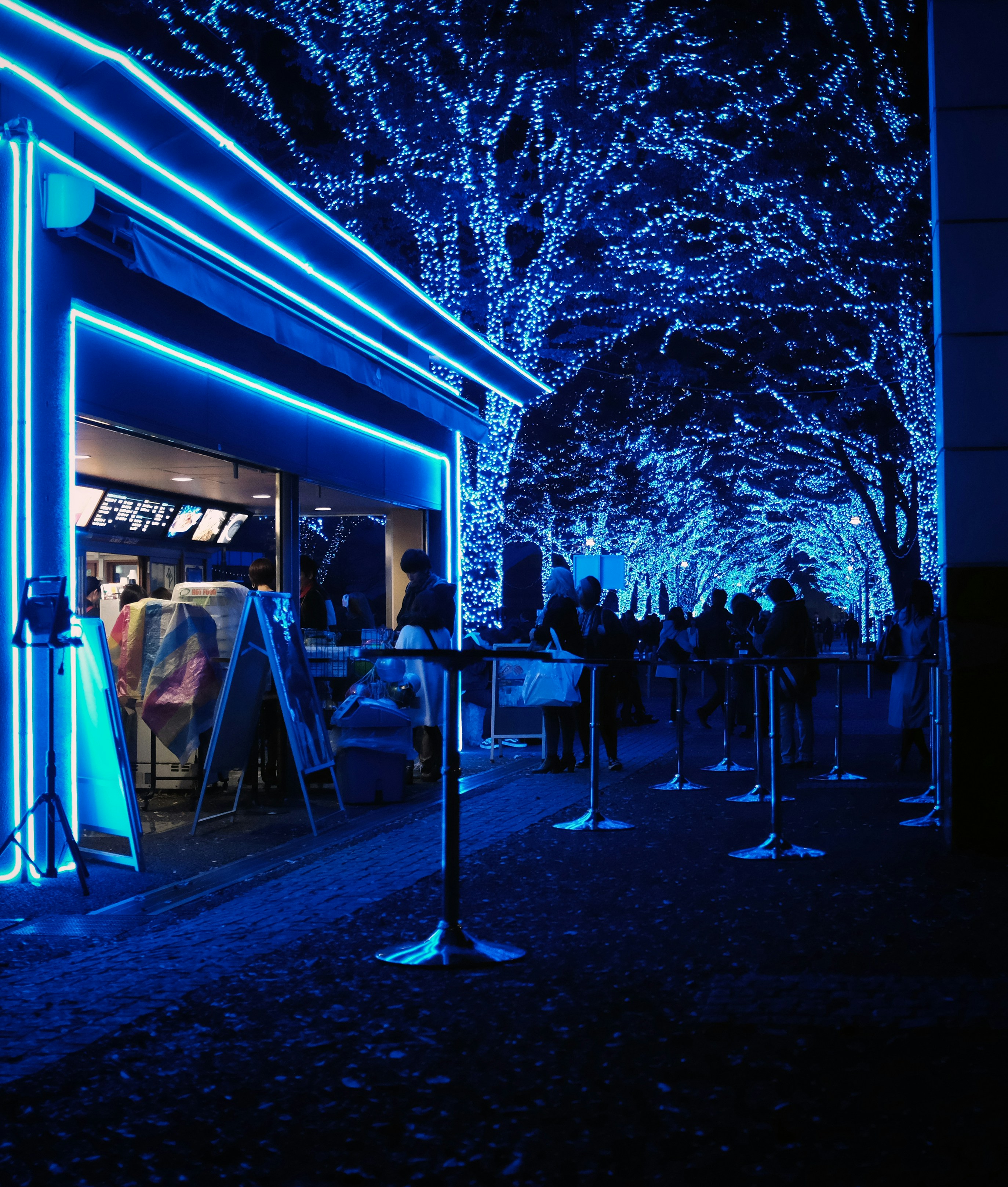 a group of people standing outside of a store at night