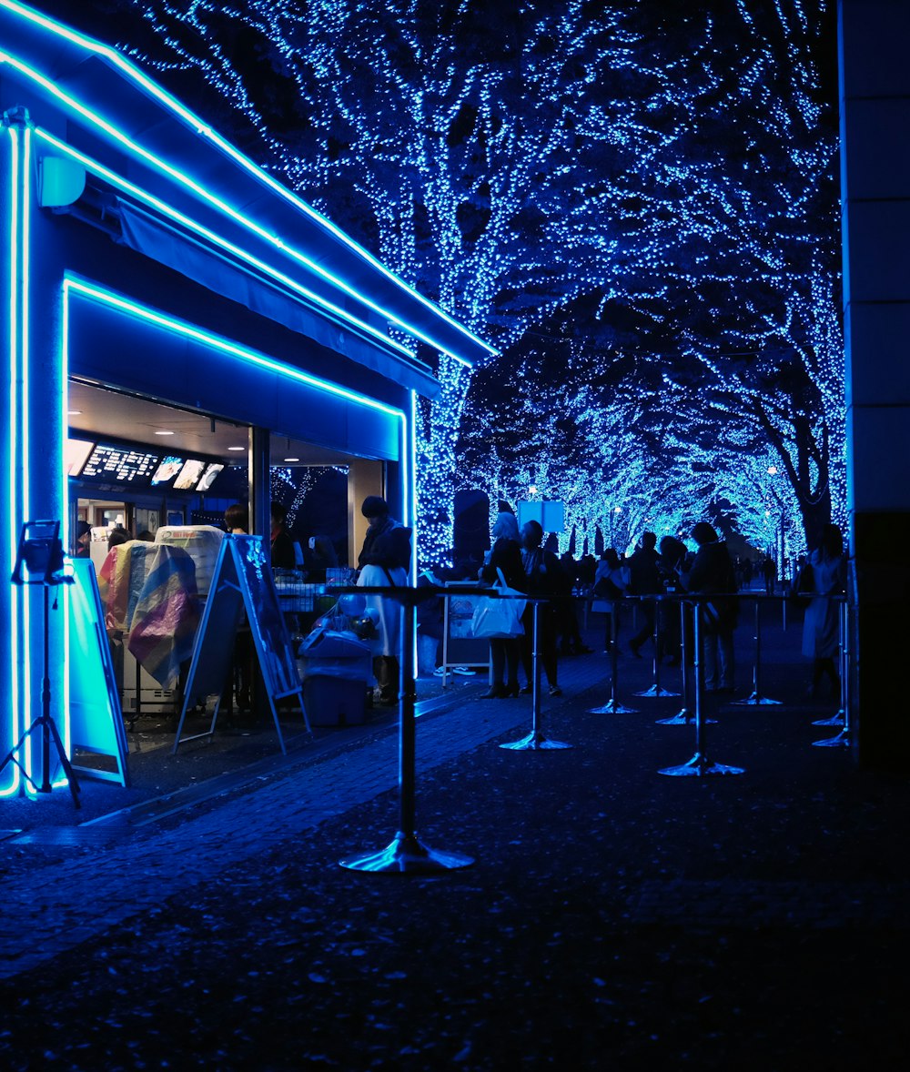 a group of people standing outside of a store at night