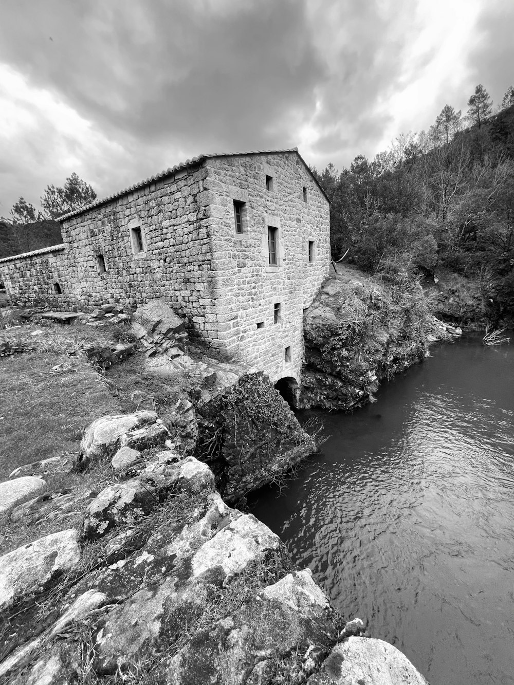 a black and white photo of a building near a river