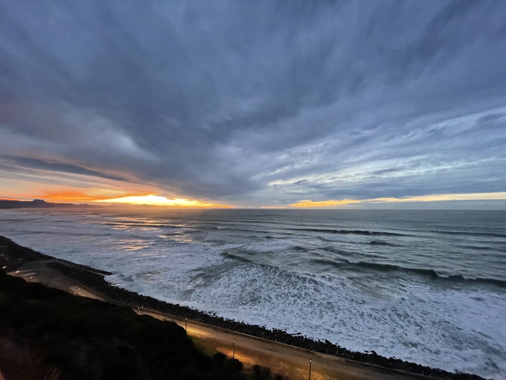 the sun is setting over the ocean and the beach