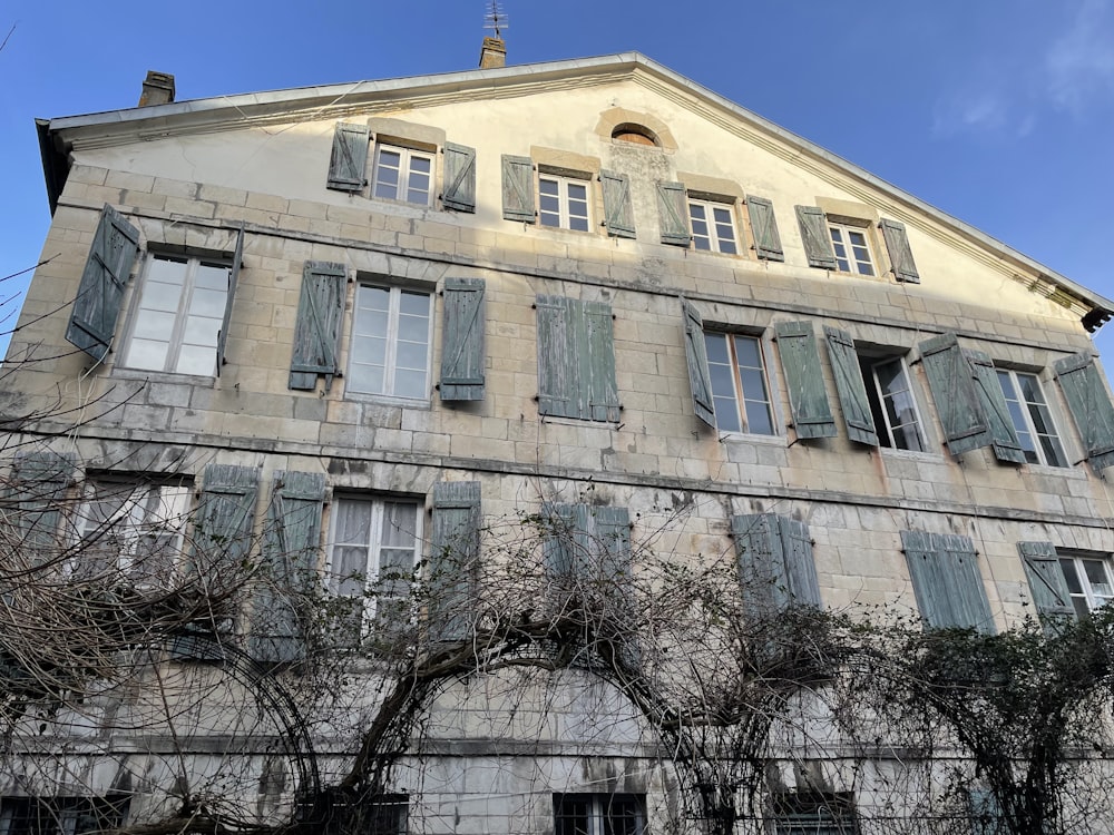 un vieux bâtiment avec des volets verts et du lierre qui pousse dessus