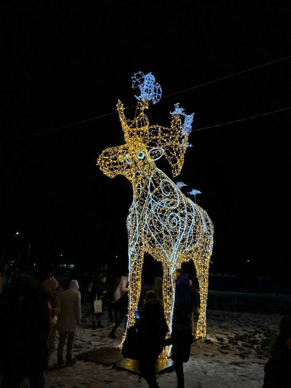 eine Lichtskulptur eines Rentiers mit einem Vogel auf dem Rücken