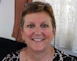 Portrait of a smiling middle-aged woman in a bright, modern clinic setting.