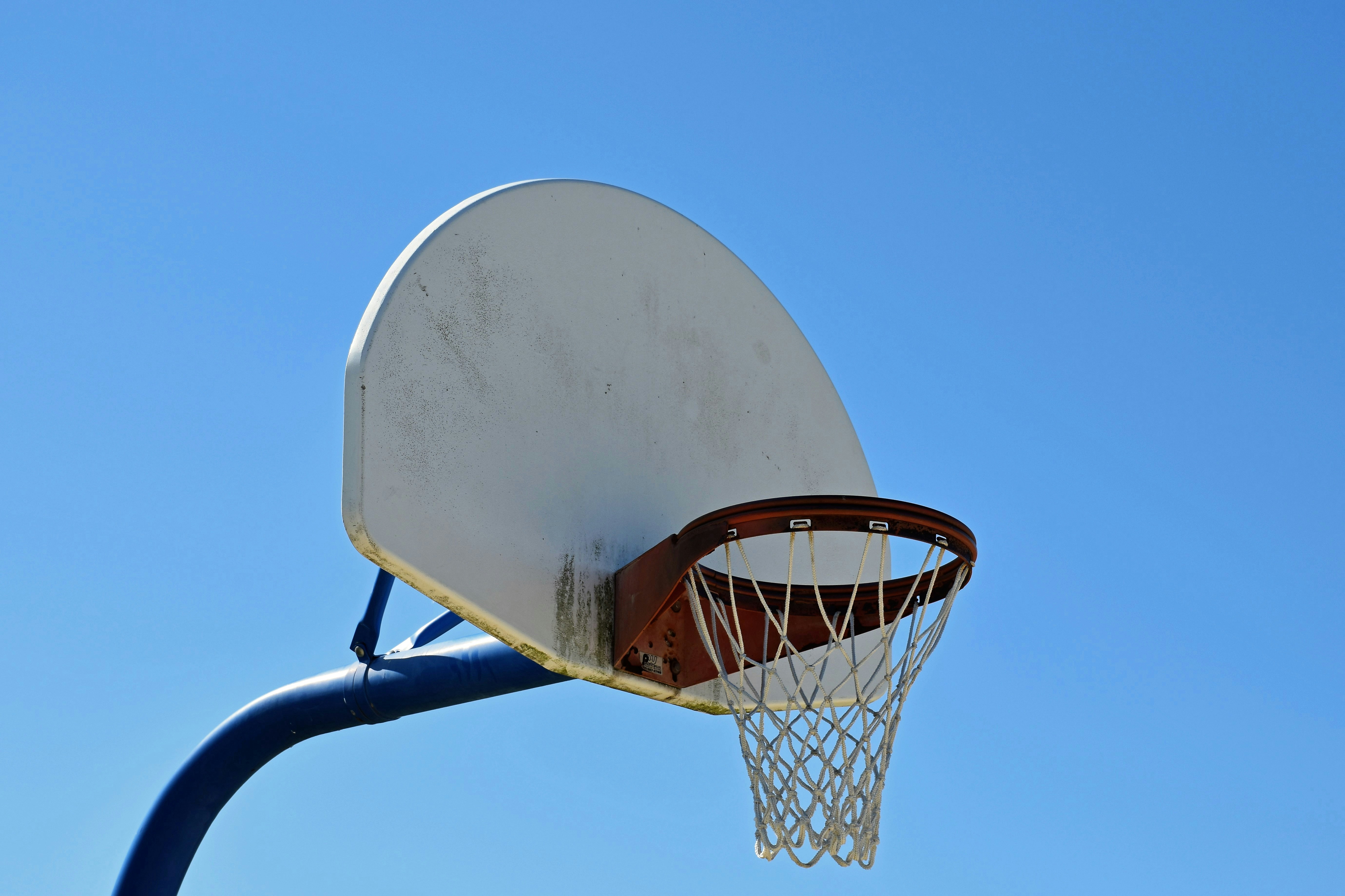 Outside basketball is fun. The photo shows a basketball hoop, net, and backboard against a clear sky.