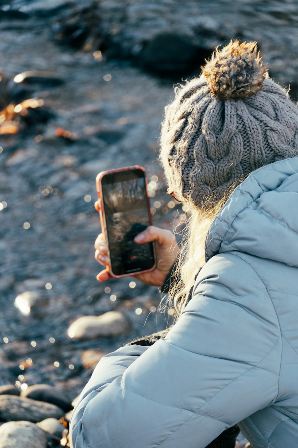 a woman is taking a picture of a river with her cell phone