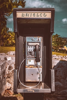 an old fashioned pay phone sitting on top of a rock