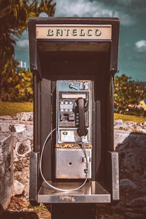 an old fashioned pay phone sitting on top of a rock
