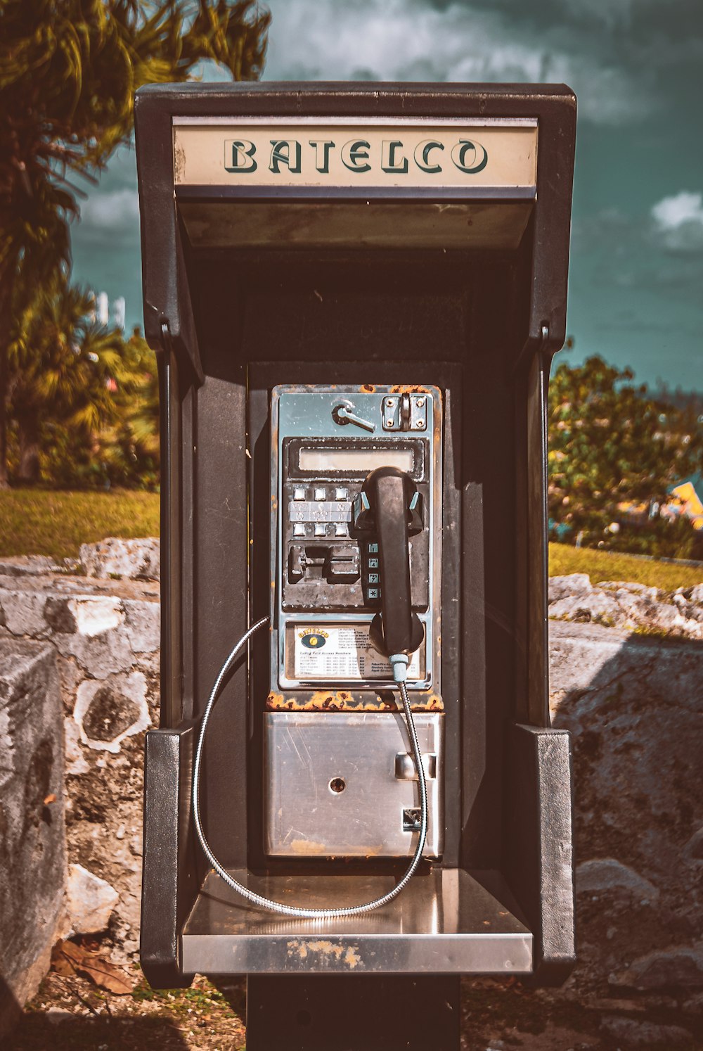 um telefone público antiquado sentado em cima de uma rocha