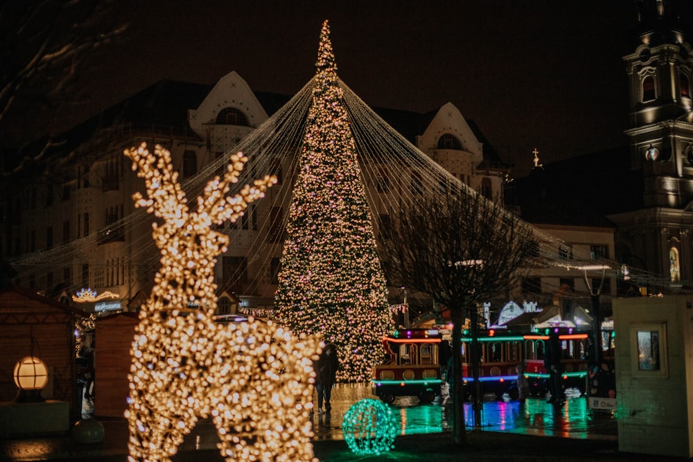 a lit up christmas tree in front of a building