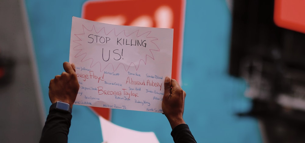 a person holding a sign that says stop killing us