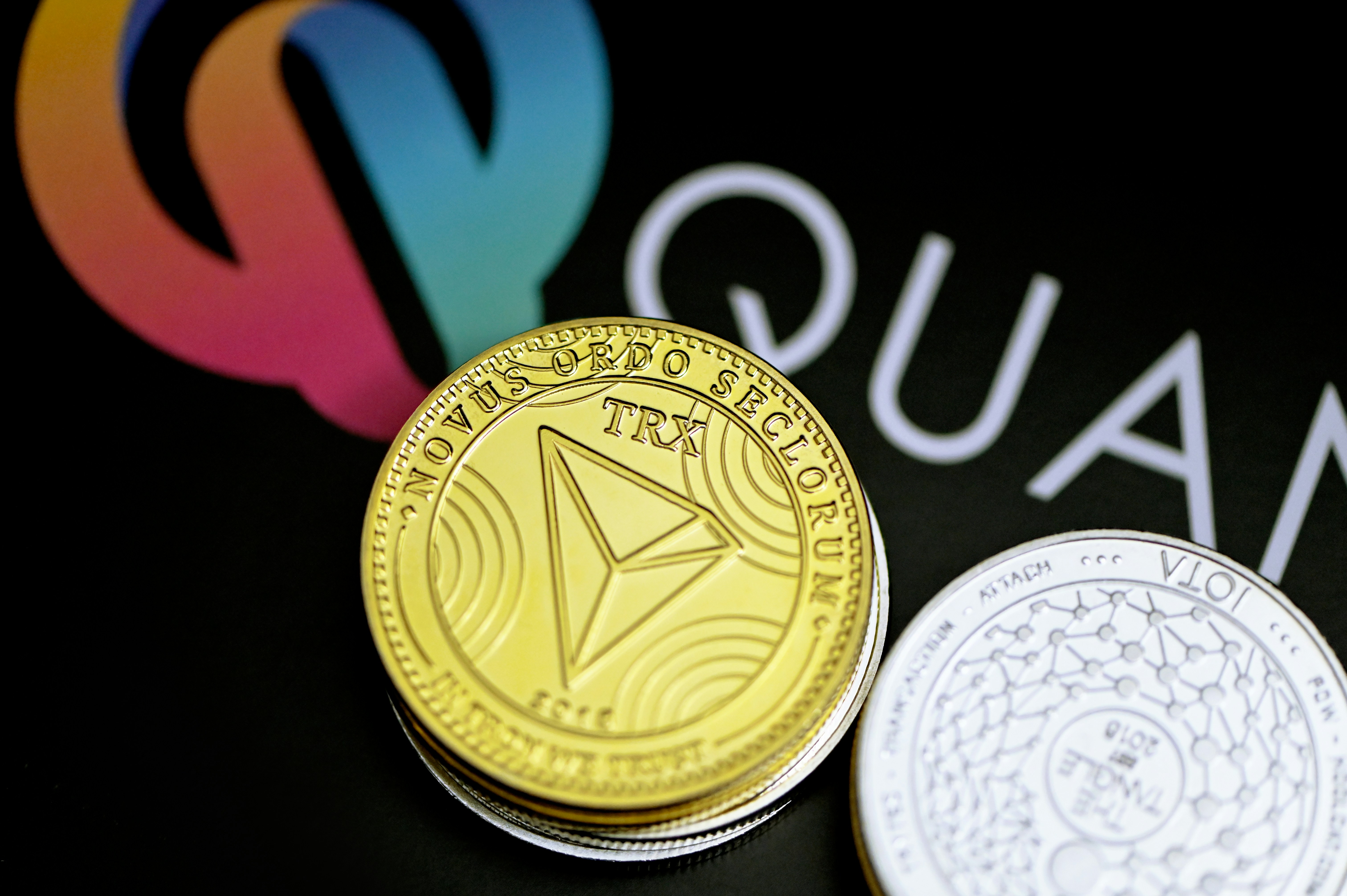 Tron coin and IOTA coin on top of the Quantitatives background