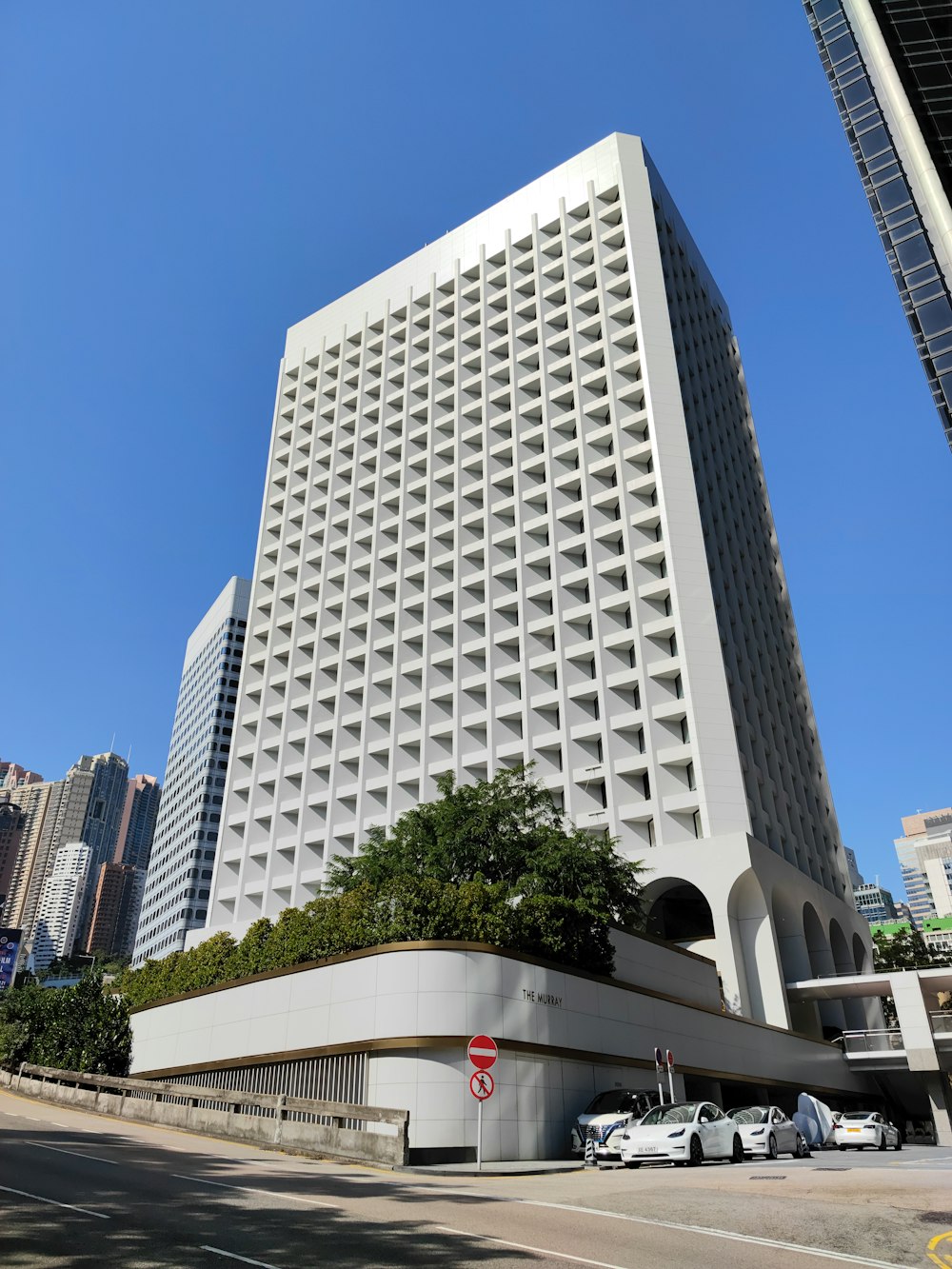 a very tall white building with a bunch of cars parked in front of it