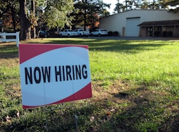 a now hiring sign in front of a building