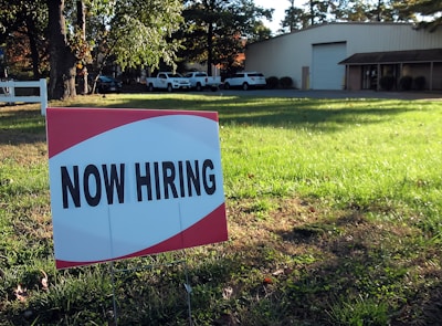 a now hiring sign in front of a building