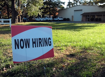 a now hiring sign in front of a building